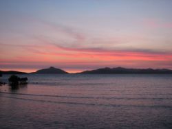 The sun sets off shore at Loloata Resort off the mainland... by Jerry Hamberg 